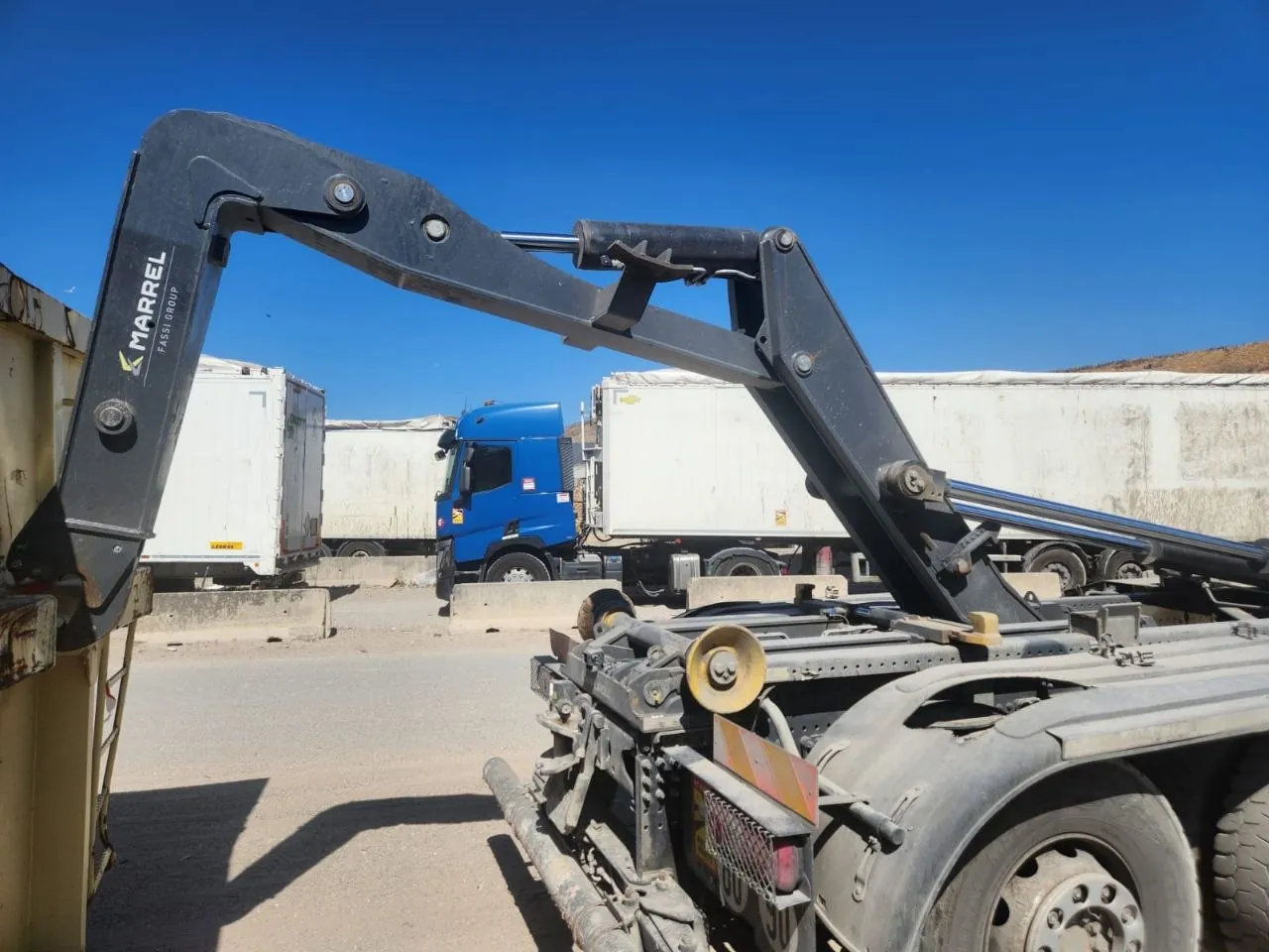 Bras de grue replié, camions à l'arrière-plan